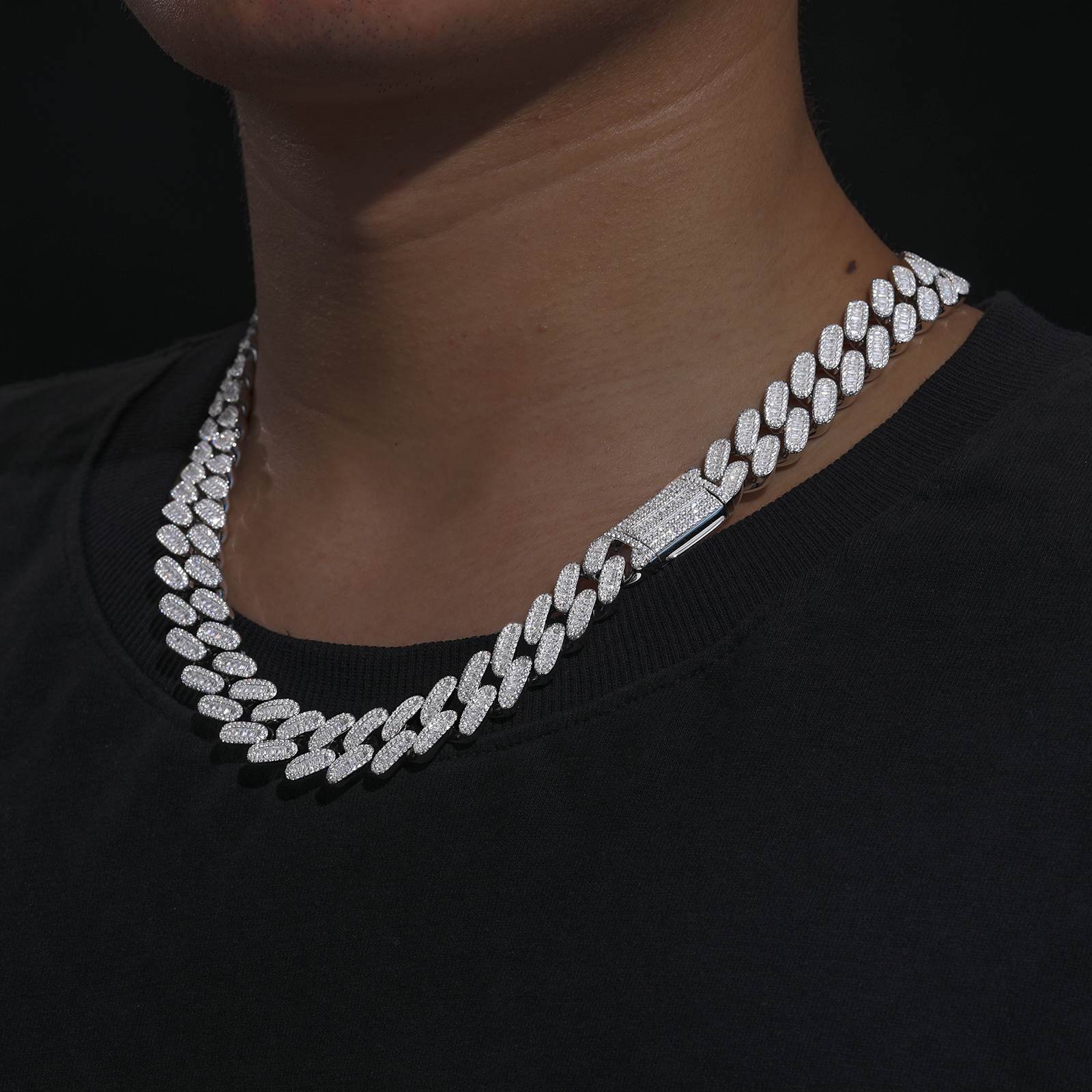 Close-up of white gold chain’s single-row baguette moissanites, reflecting studio lights for stage-ready brilliance on tattooed skin.