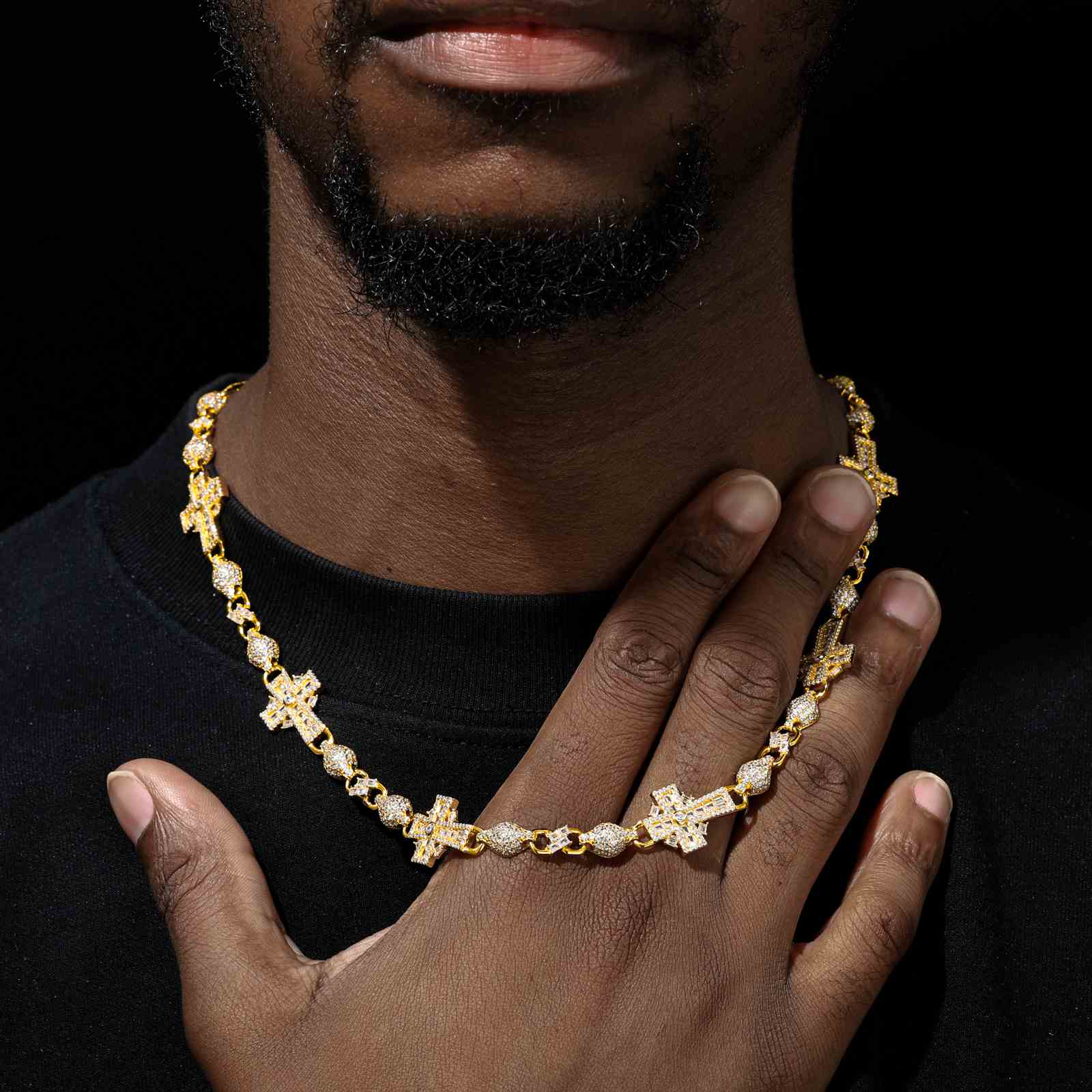 Gold-plated Celtic Cross Chain styled on a male model with layered Cuban chains, shot in a dimly lit studio for contrast.
