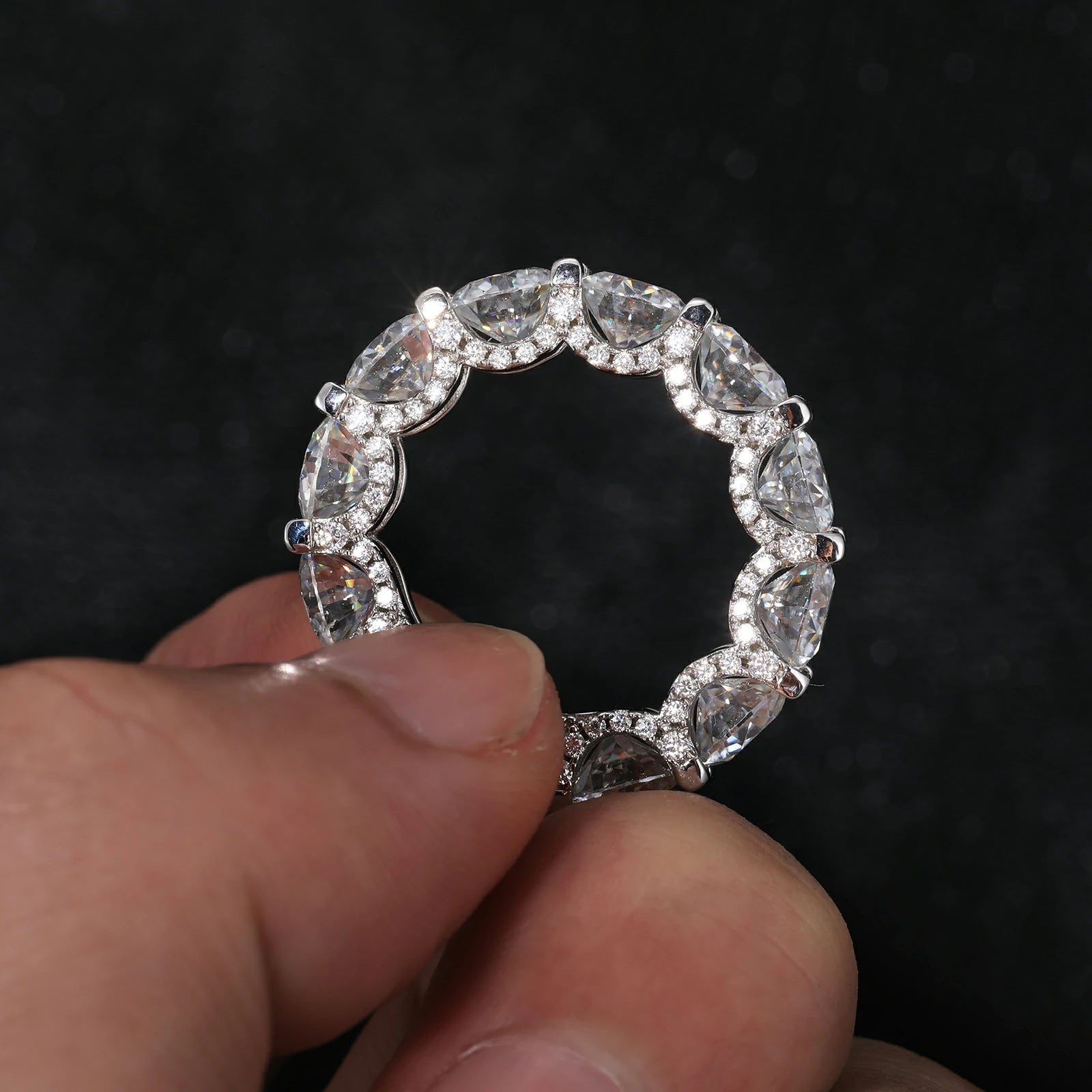 Close-up of hand presenting a white gold moissanite eternity ring, featuring 6.5mm center stone and hypoallergenic S925 silver band.