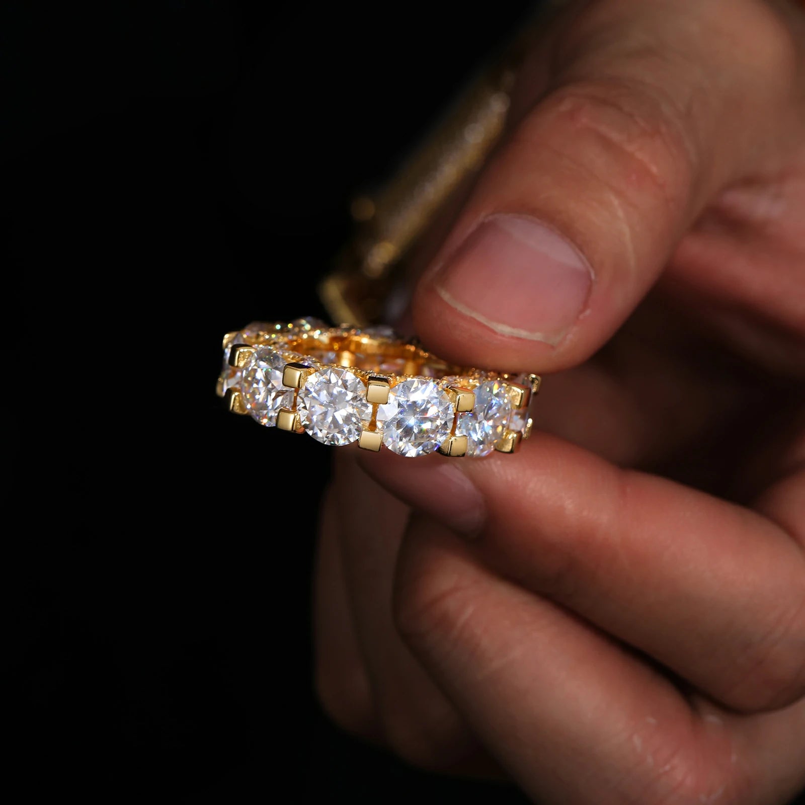 Hand holding a 6.5mm yellow gold moissanite eternity ring, emphasizing secure prong settings and lab-created stone clarity.