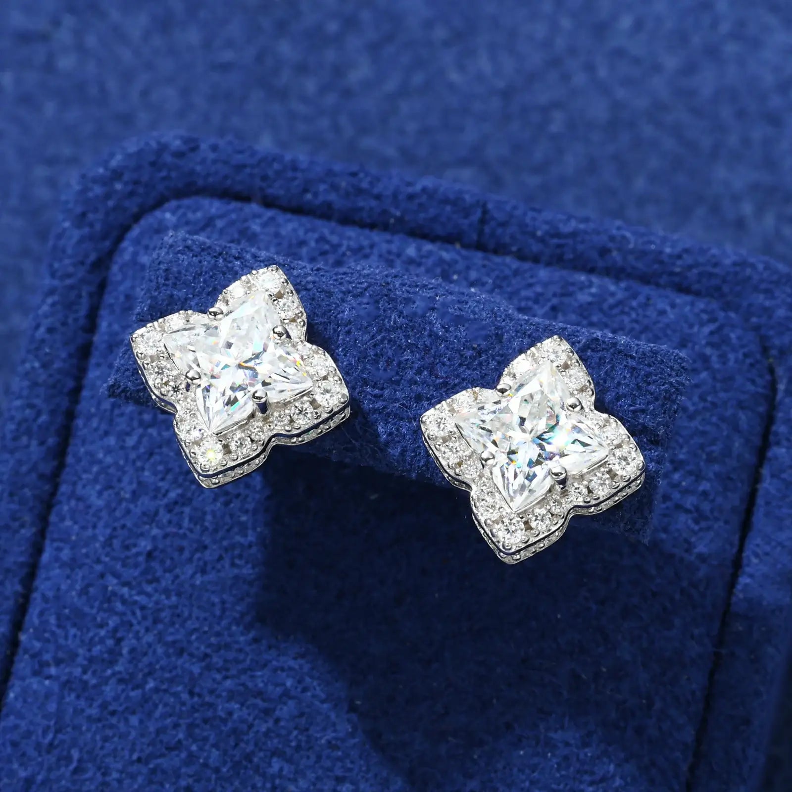 Front close-up of white gold 925 sterling silver lily cut moissanite star stud earring on blue table — highlighting lily-cut moissanite sparkle, geometric star detail, 925 silver build