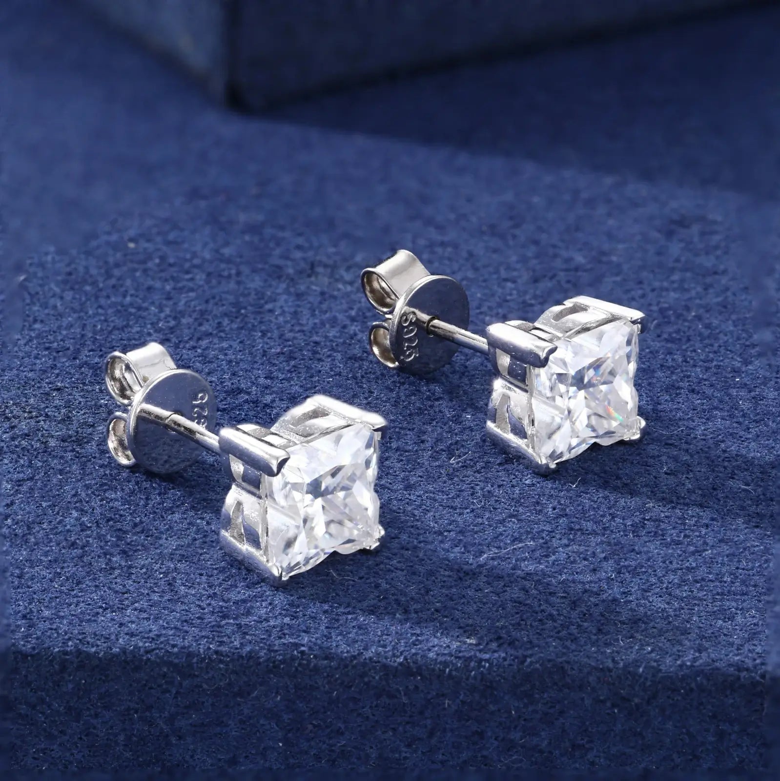 Side close-up of white gold 925 sterling silver lily cut moissanite stud earring on blue table — highlighting lily-cut moissanite detail, 925 silver setting, geometric sparkle