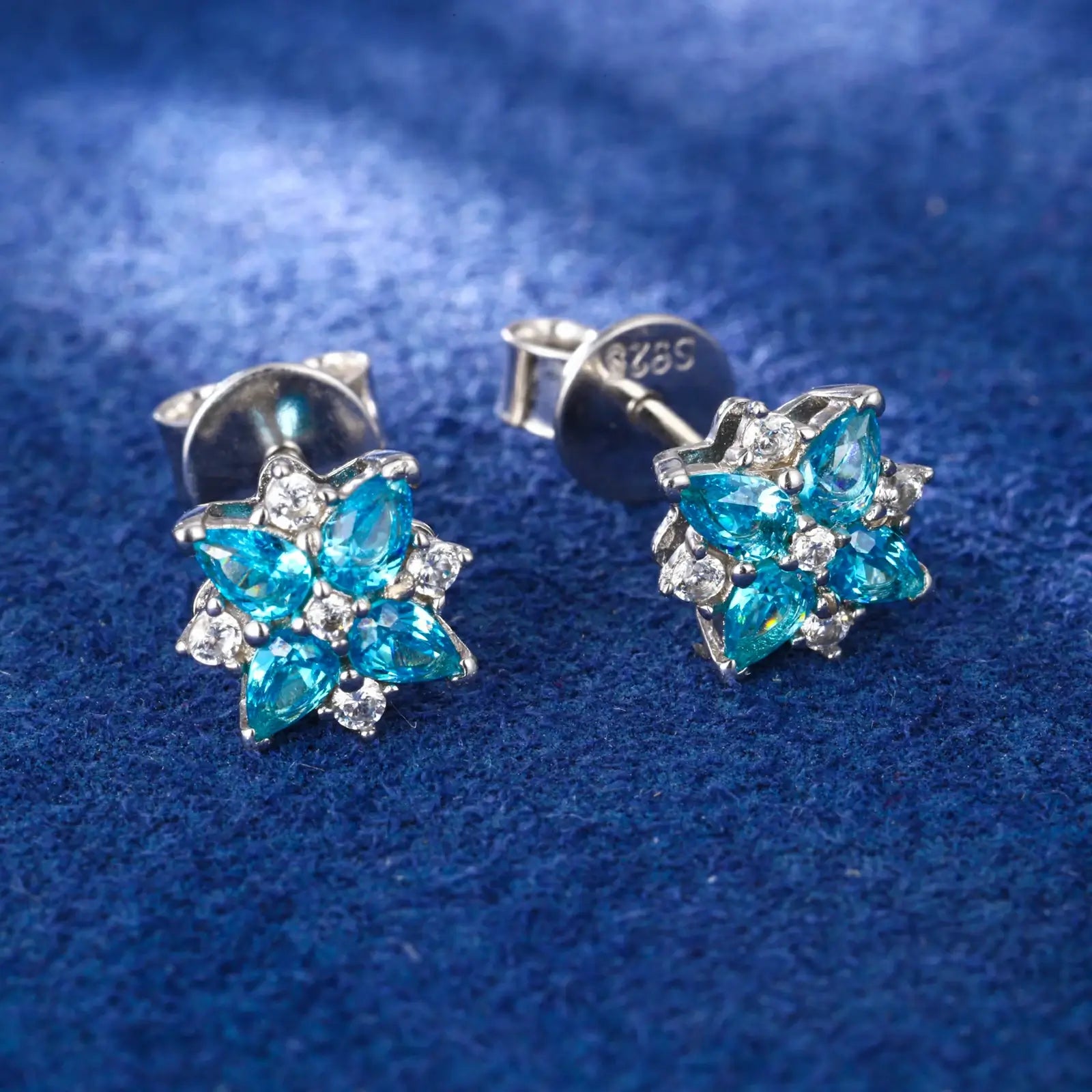 Side close-up of white gold 925 sterling silver moissanite lucky star clover stud earring on blue table — highlighting moissanite & zircon detailing, star-clover texture, 925 silver build