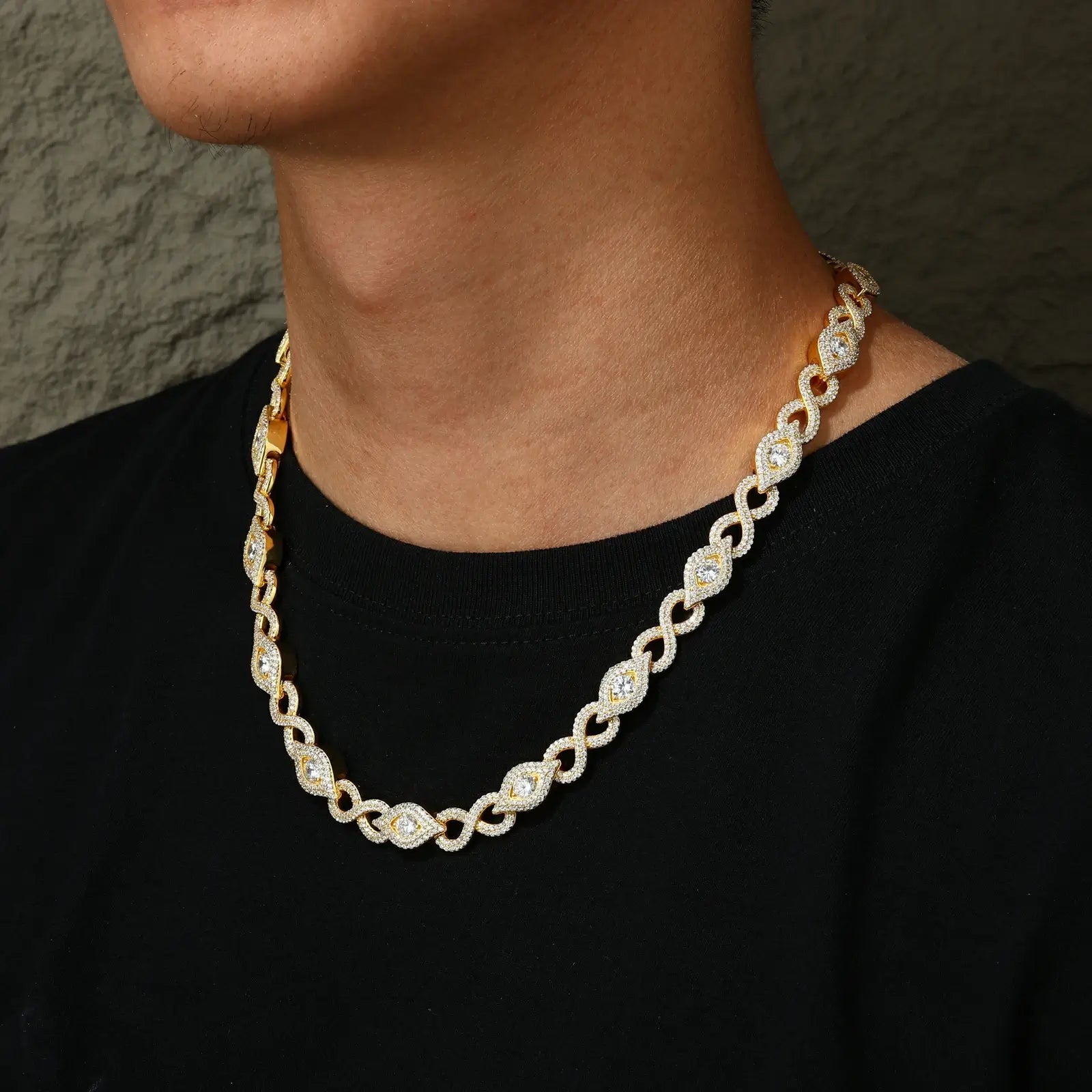 Gold plated Evil Eye chain on African American model - 10mm Cuban links with VVS moissanite stones refracting light in sunlit environment