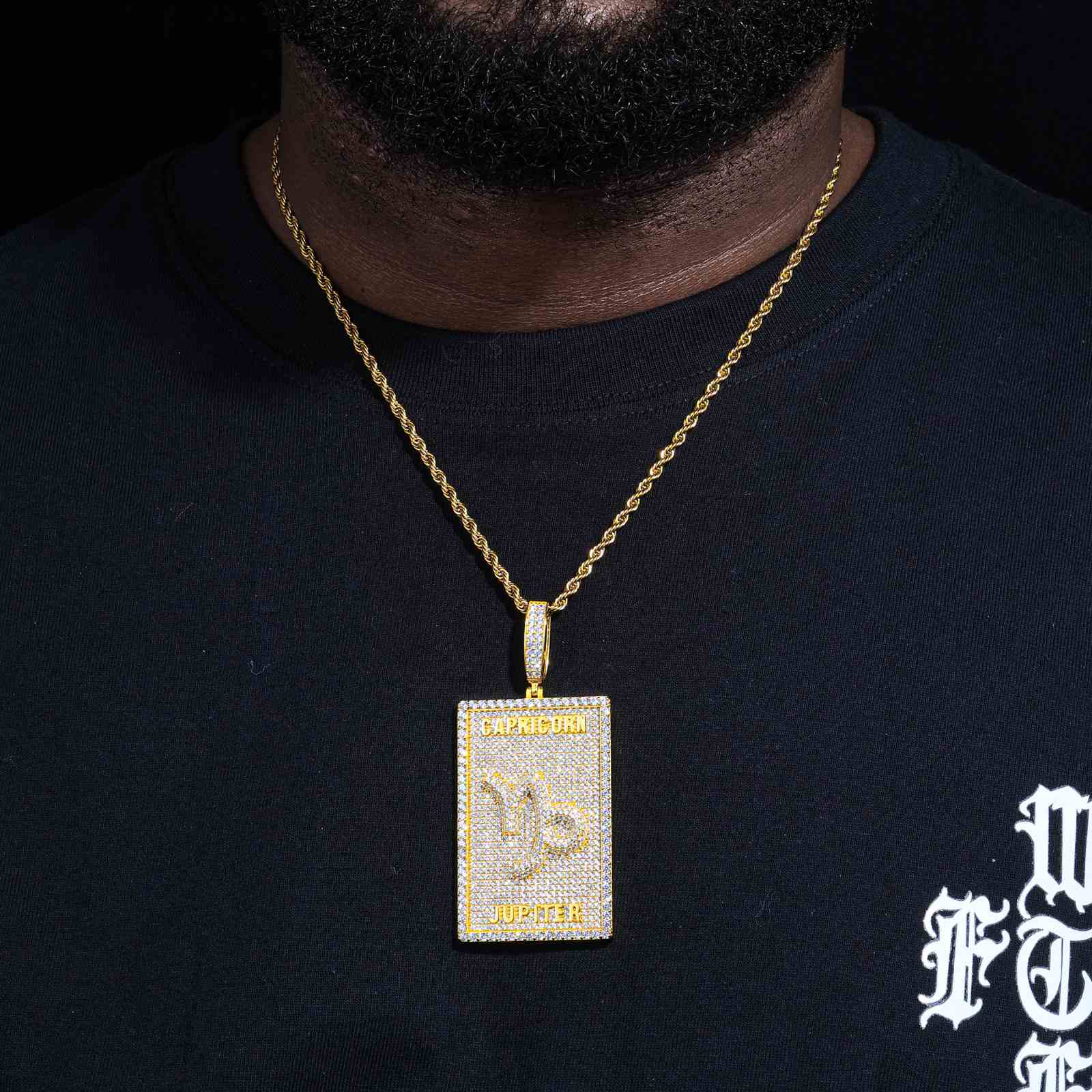 Black male model wearing S925 Capricorn zodiac dog tag necklace with 300+ micro-paved moissanites, layered with thick Cuban link chain in urban streetwear style