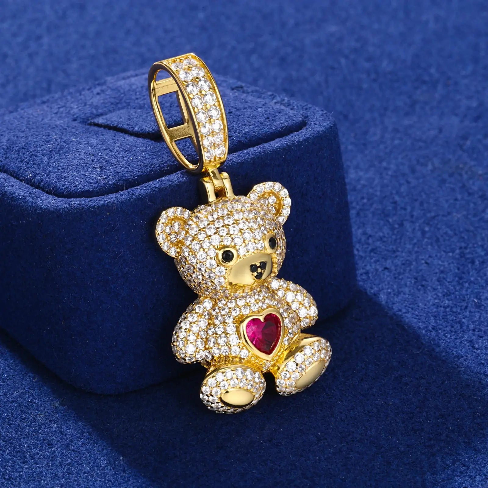 Side view of gold sweetheart bear pendant on blue table - showing 3D design with red zircon heart and moissanite accents
