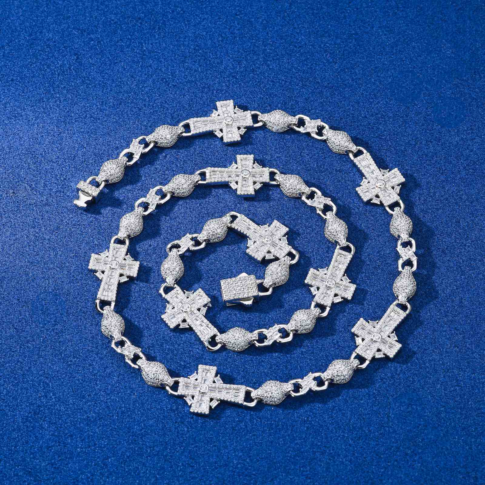 14mm Celtic Cross Chain with baguette moissanites laid on a navy blue marble table, showcasing reflective sparkle under studio lighting