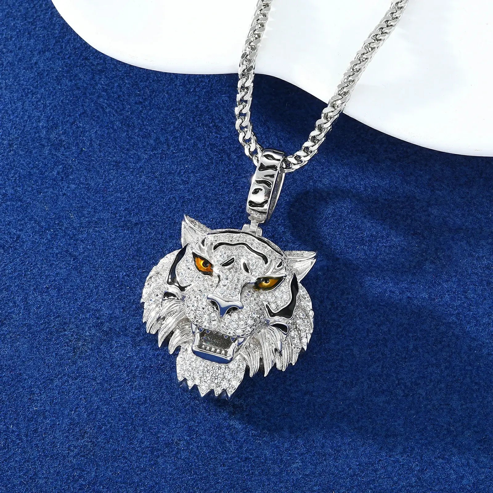 S925 white gold moissanite tiger head pendant displayed on blue velvet surface, highlighting the 3D depth and ice.