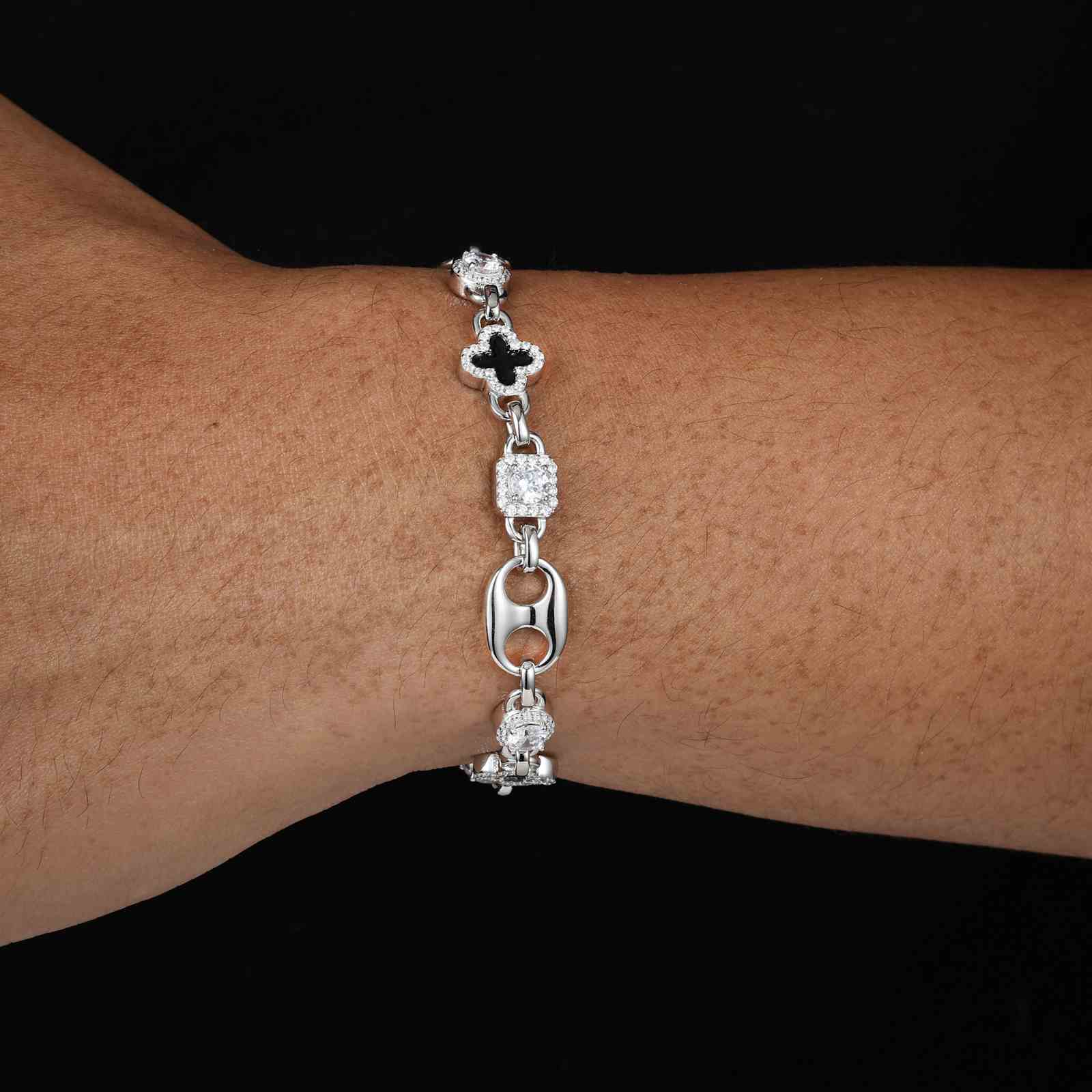 Male model styling the white gold-plated clover bracelet with rolled denim sleeves, showcasing hip-hop casual luxury.
