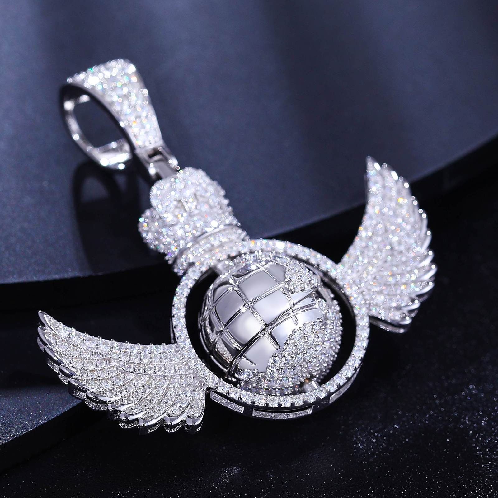 Top-down view: Spinning globe pendant with moissanite oceans on marble - wing articulation detail | ISO 9227 tarnish-proof certification