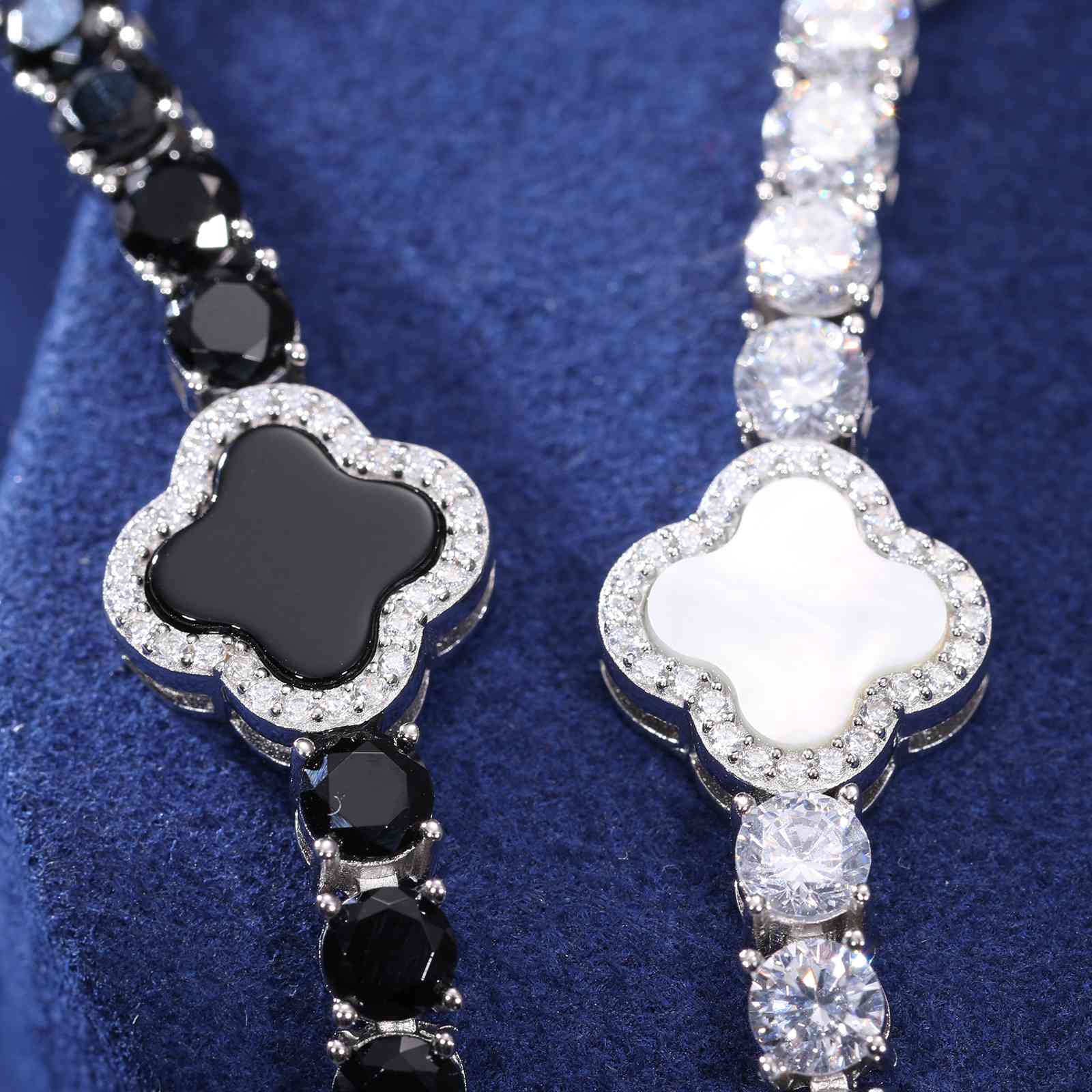Close-up of white and black enamel clovers with moissanite accents, blending organic motifs and modern minimalist design.