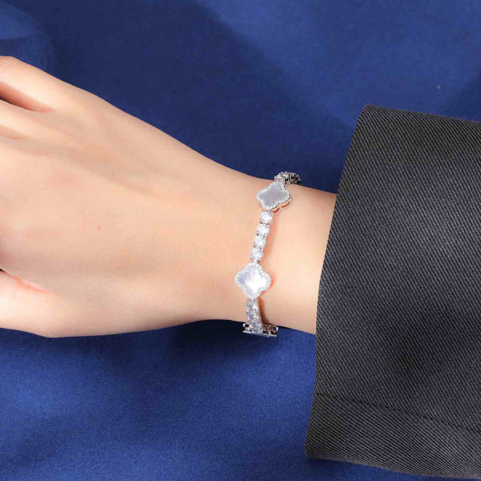 Elegant white enamel four-leaf clover tennis bracelet worn by model, radiating celestial moissanite brilliance and timeless charm.