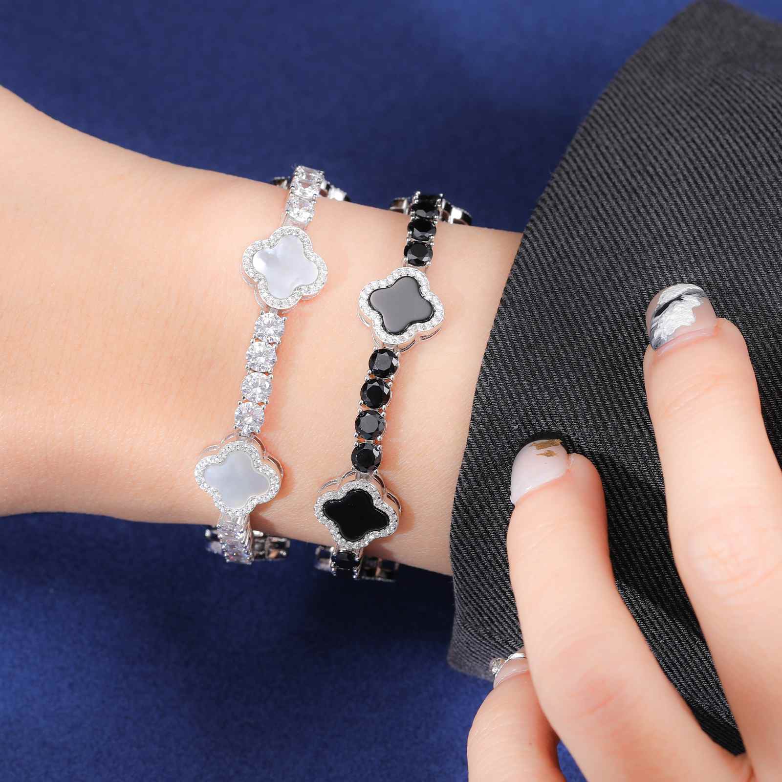 Stylish model wearing white and black enamel four-leaf clover bracelets, highlighting contrasting moissanite sparkle and S925 silver elegance.