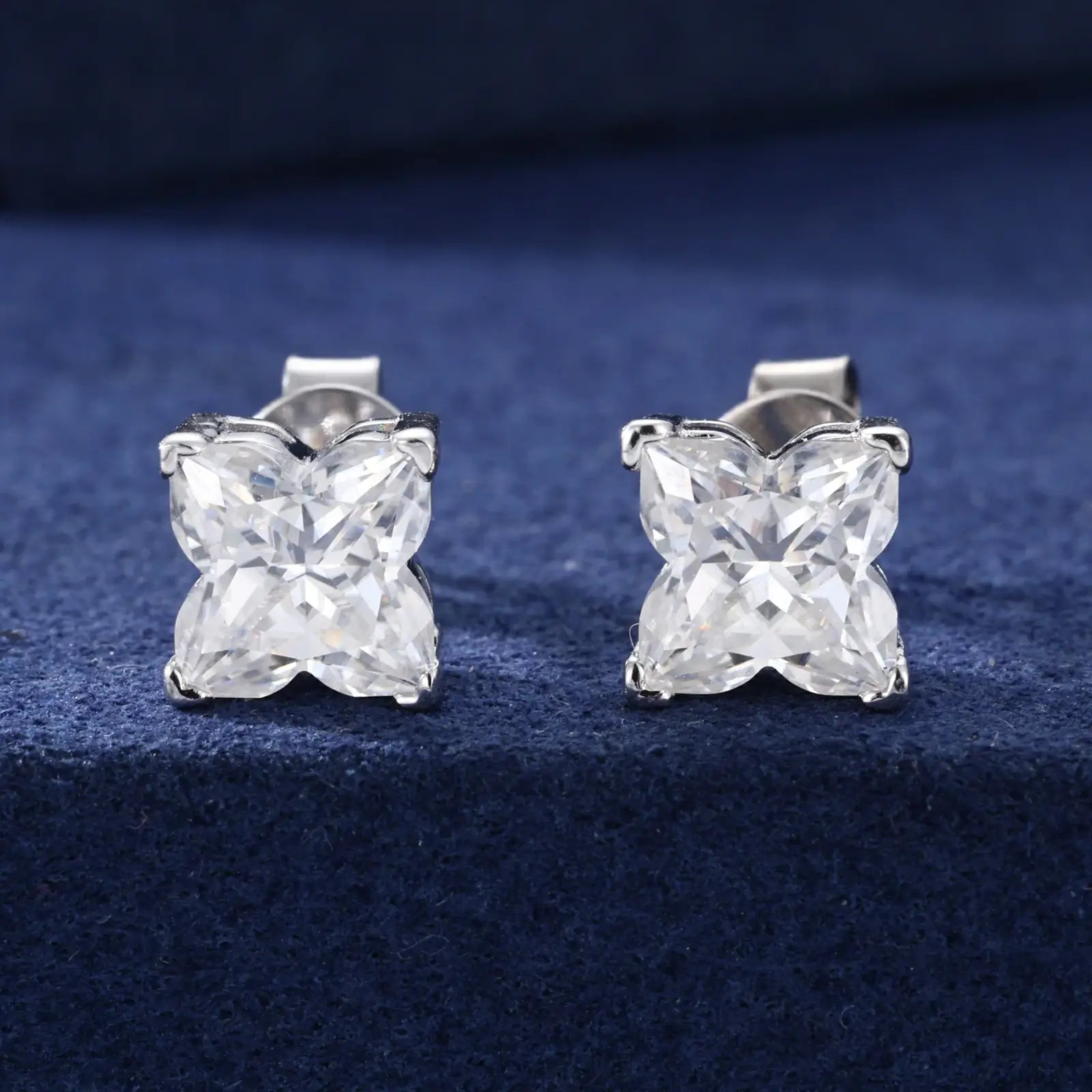 White gold 925 sterling silver lily cut moissanite stud earrings full display on blue table — showcasing lily-cut design, moissanite sparkle, 925 silver craftsmanship