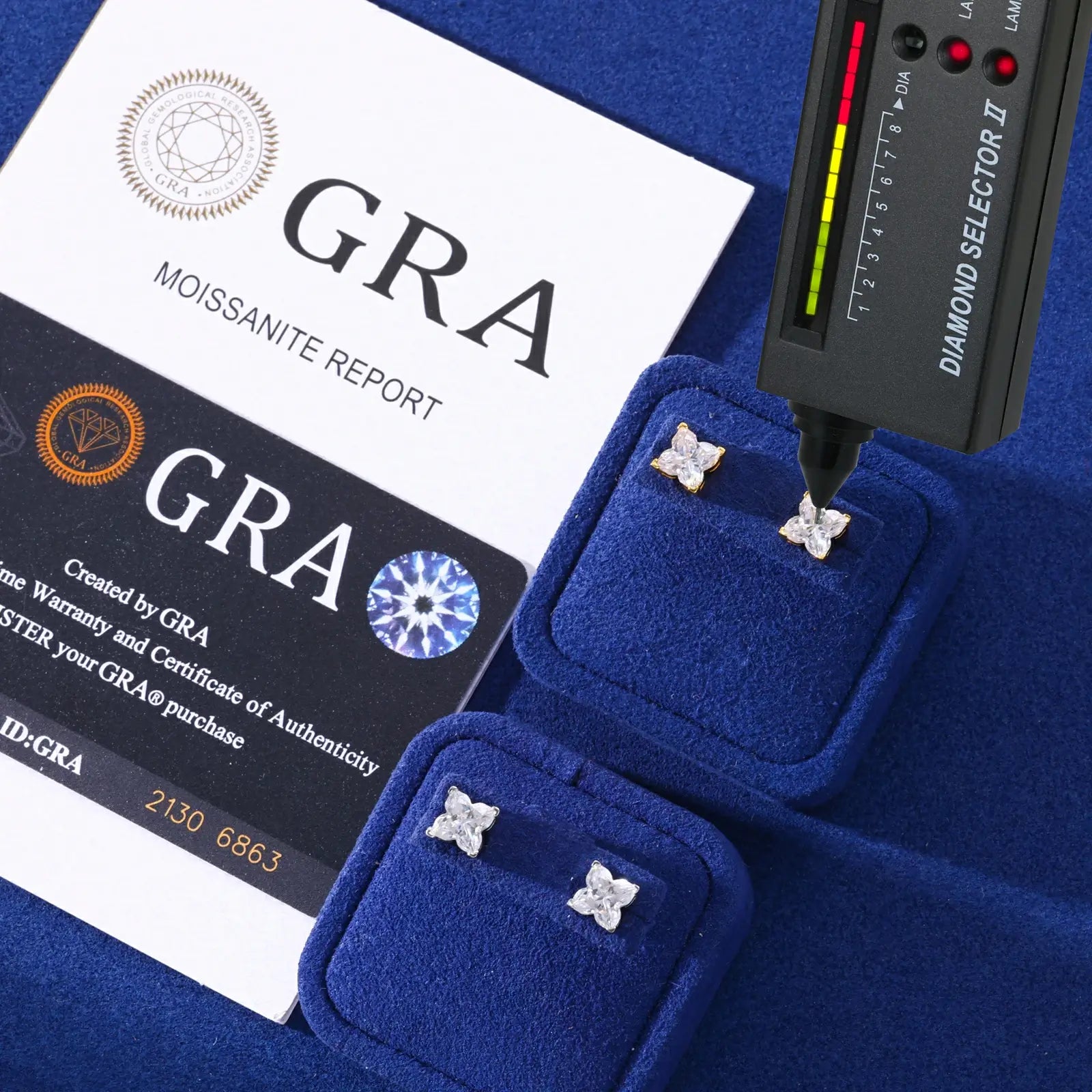 White & yellow gold 925 sterling silver lily cut moissanite stud earrings with diamond tester + GRA certificate on blue table — certified moissanite, 925 silver durability, unique lily-cut design