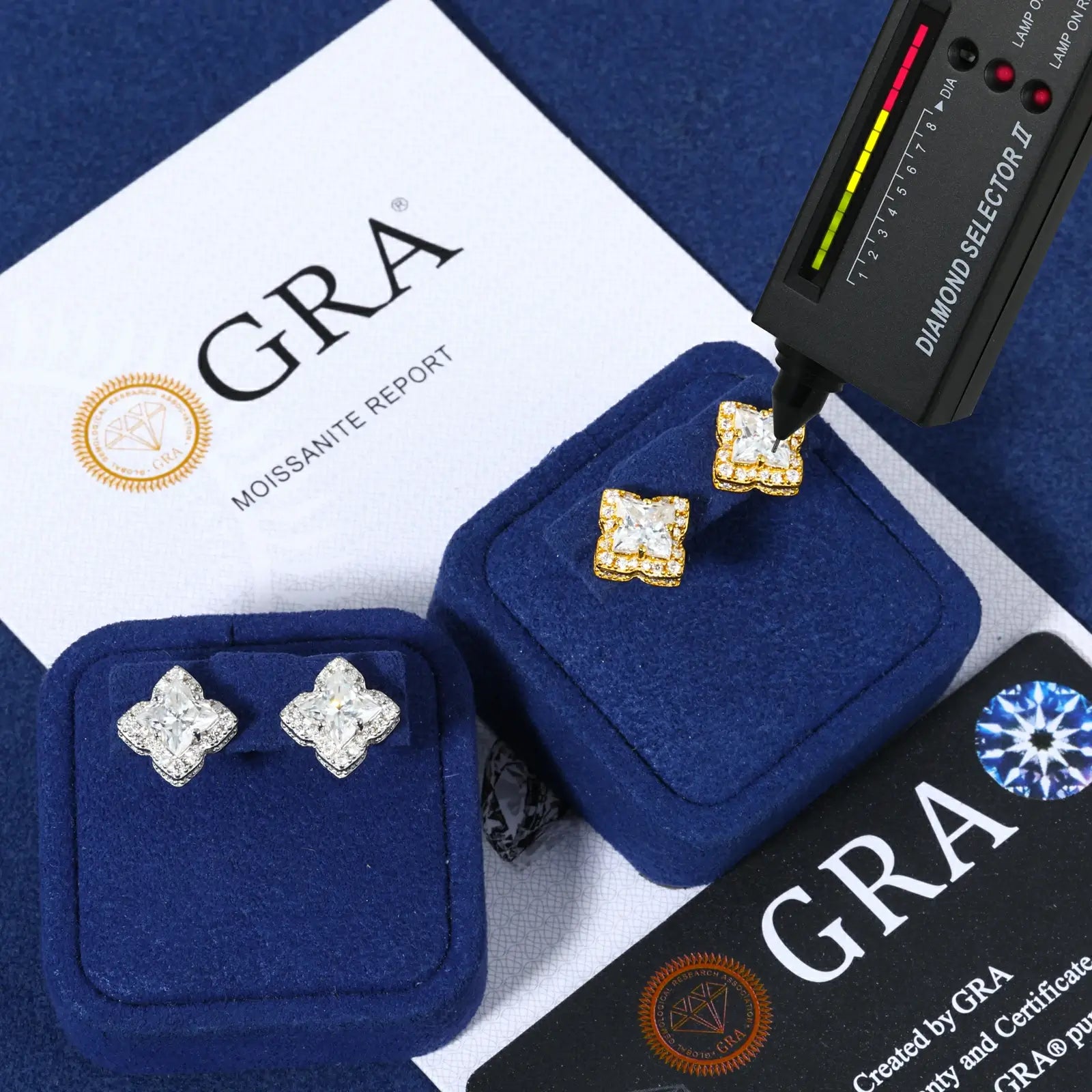 White & yellow gold 925 sterling silver lily cut moissanite star stud earrings with diamond tester + GRA certificate on blue table — certified moissanite, 925 silver durability, geometric star design