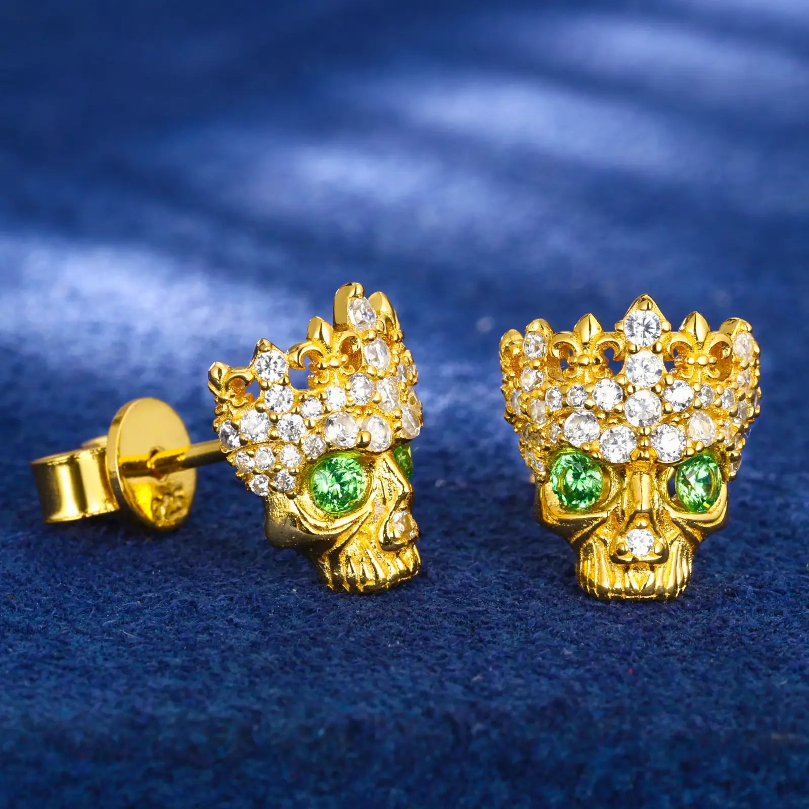 Side close-up of yellow gold 925 sterling silver moissanite Chrome Hearts crown skull stud earring on blue table — highlighting moissanite & zircon detailing, crown-skull texture, 925 silver build