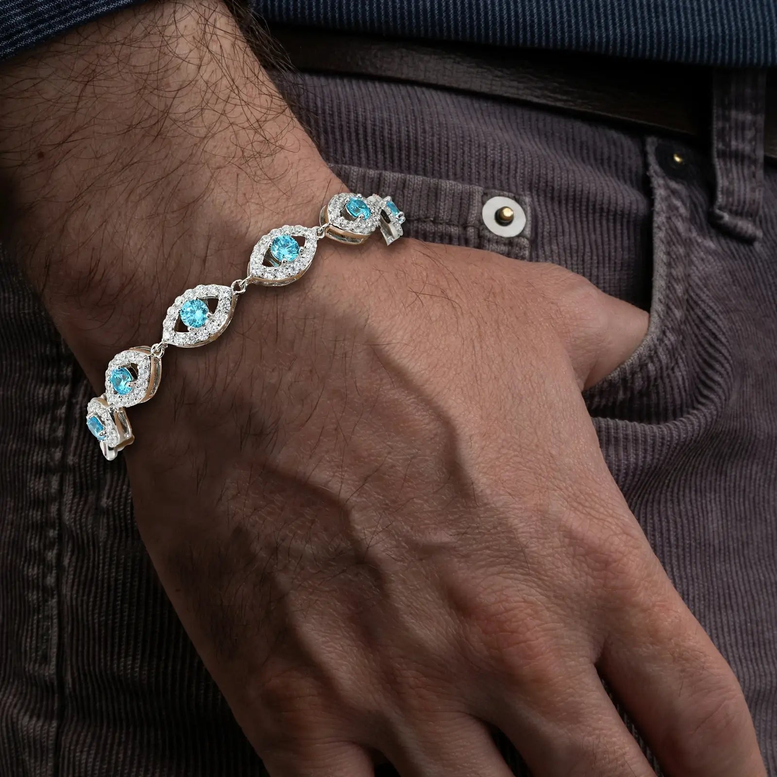 African American man wearing S925 white gold-tone evil eye bracelet with blue moissanite center - 14mm links radiating 2.65 RI protection | Street-luxe spiritual armor