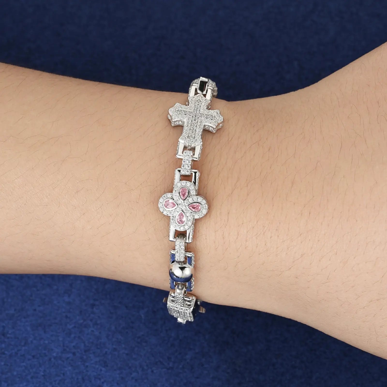 Caucasian model wearing 14mm white gold S925 bracelet - pink moissanite clovers and diamond-cut crosses shining at garden party