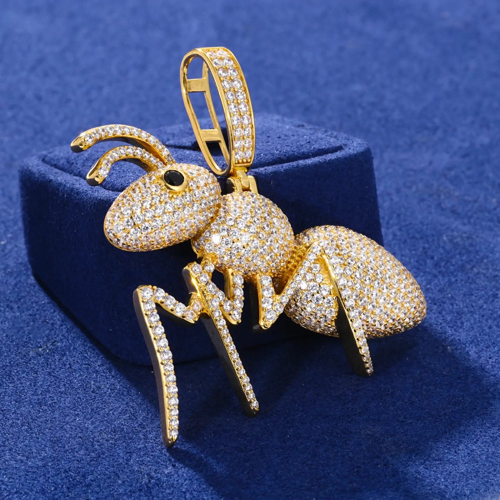 Profile view of gold ant pendant leaning on blue surface - 3D anatomical design with precise moissanite stone placement