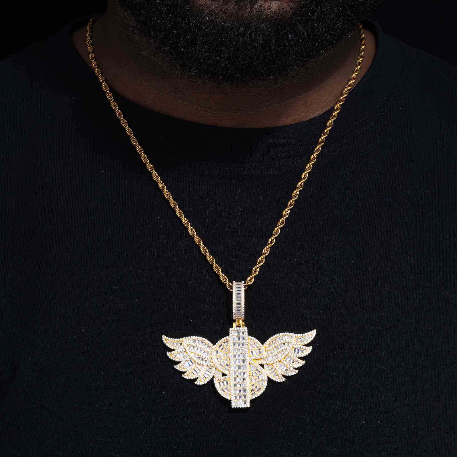 Close-up of moissanite dollar wing pendant on male model’s chest, showcasing 24K anti-tarnish gold plating and prong settings with Cuban link chain